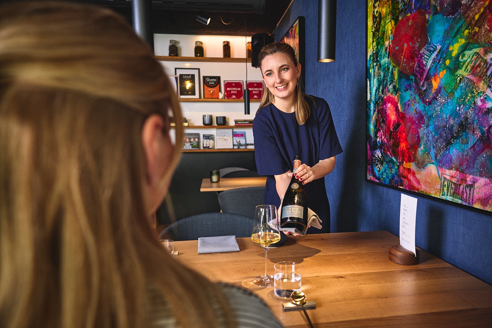 Servicekraft präsentiert Sekt am Tisch im Restaurant