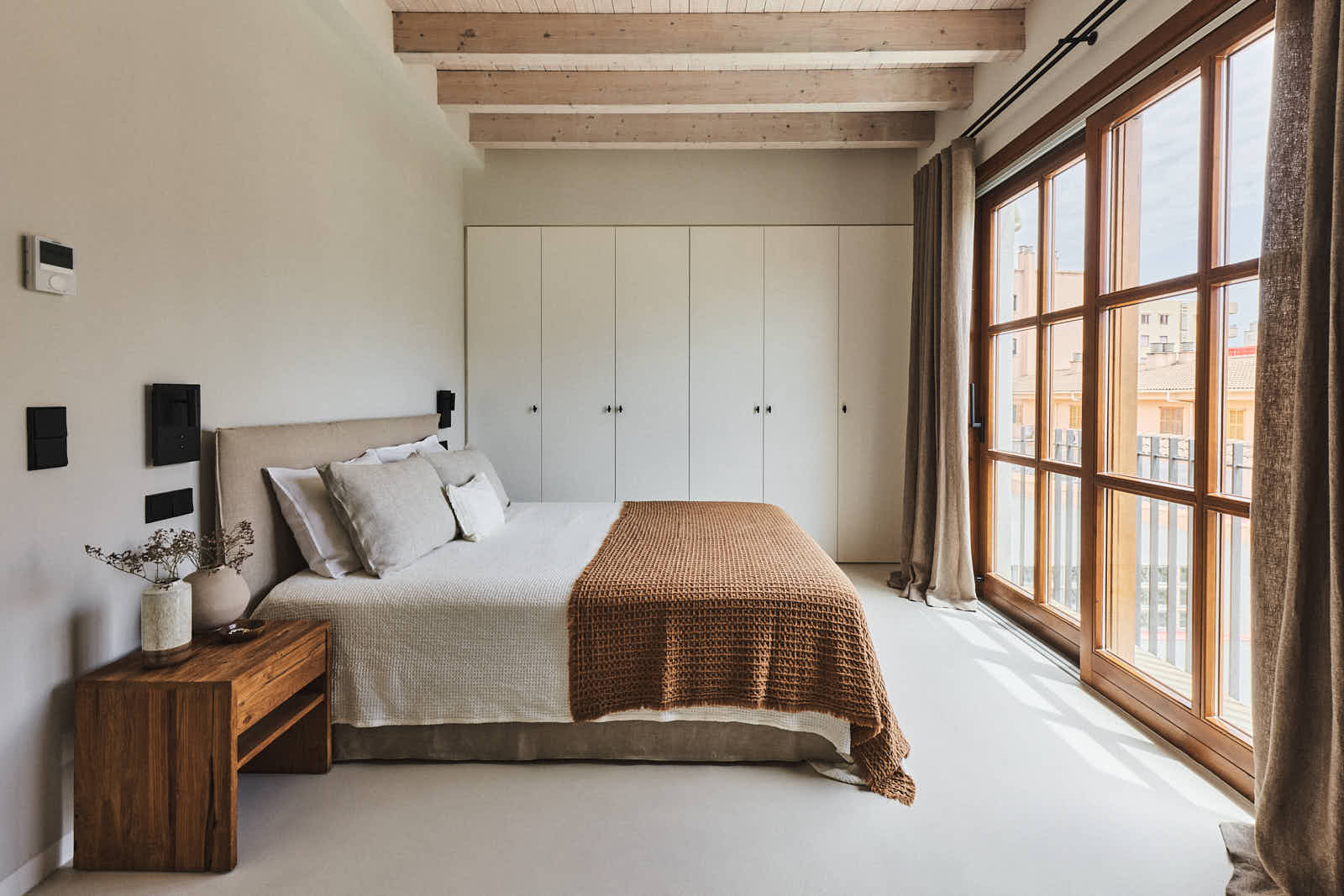 Schlafzimmer mit großen Holzfenstern