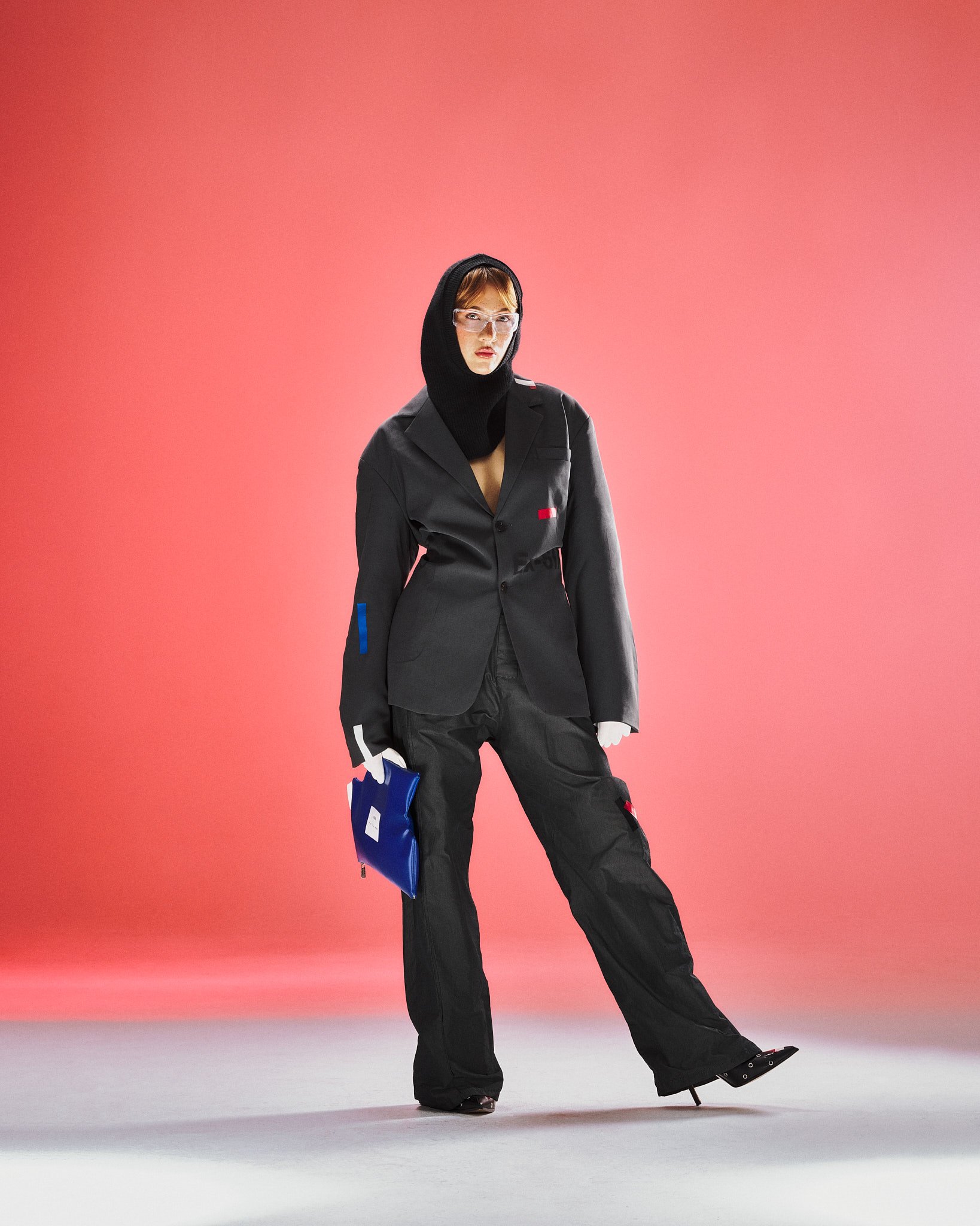 Schwarzer Anzug mit Maske und blauer Clutch, roter Hintergrund
